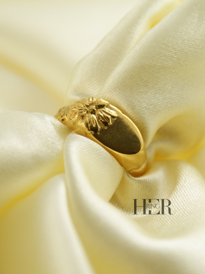 Damski sygnet Relief z kwiatem nachodzącym na taflę, wykonany w srebrze próby 925 złoconym 24-karatowym złotem, rzeźbiarska forma.