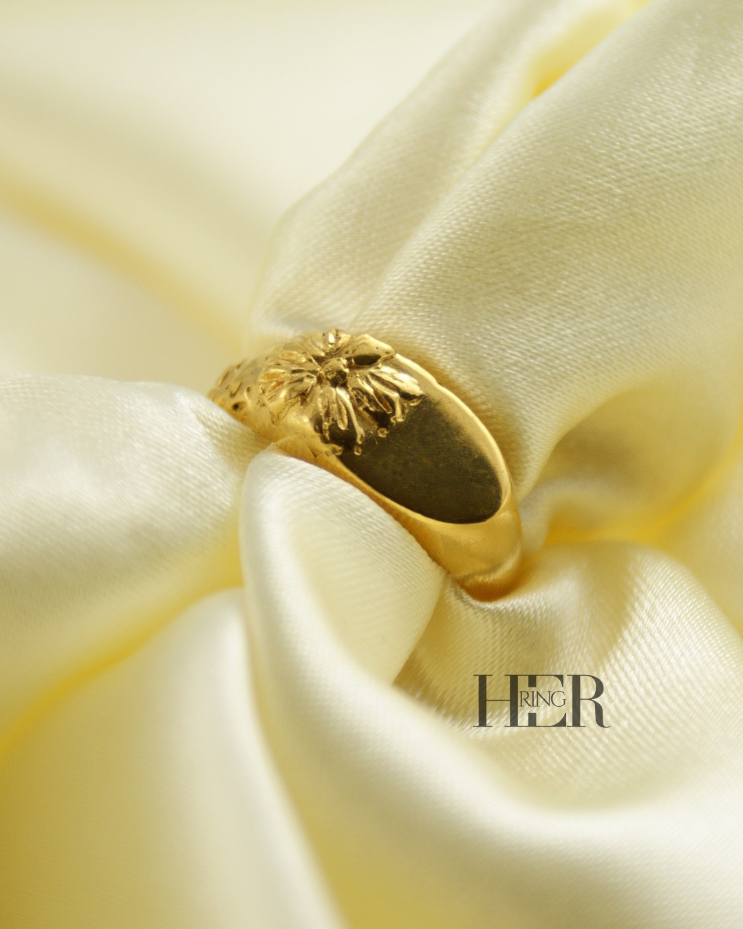 Damski sygnet Relief z kwiatem nachodzącym na taflę, wykonany w srebrze próby 925 złoconym 24-karatowym złotem, rzeźbiarska forma.