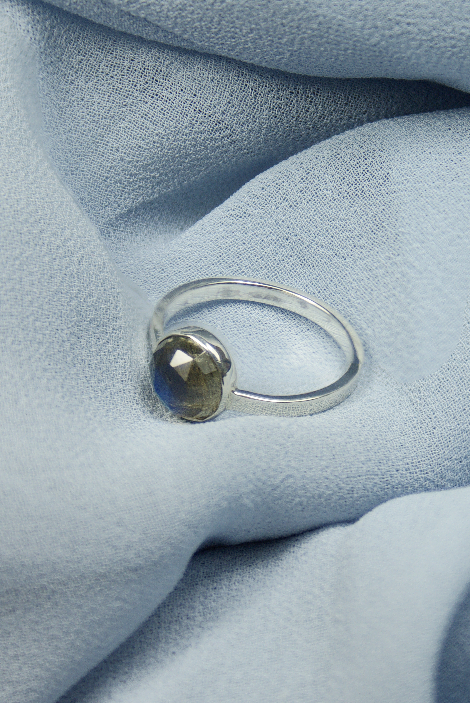 Detal szlifu rozetowego labradorytu w minimalistycznej oprawie ze srebra 925, polskie rzemiosło jubilerskie.