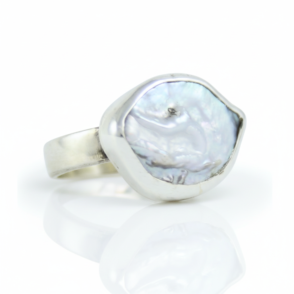 Srebrny pierścionek handmade z dużą, naturalną perłą barokową o nieregularnym kształcie na białym tle, marka Her-Ring