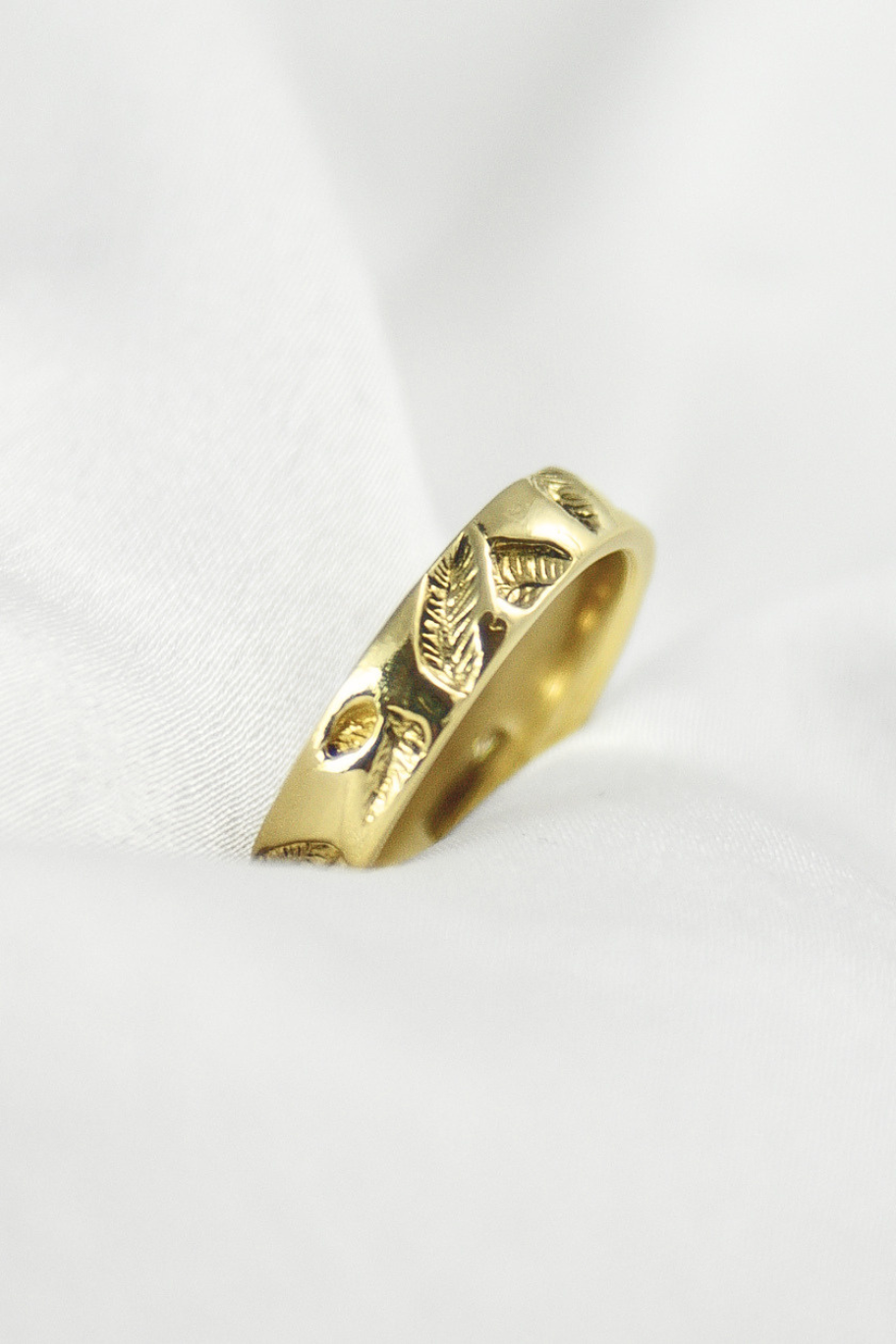 Złota obrączka Silva In z motywem roślinnym liści na białej satynie, biżuteria autorska HerRing.