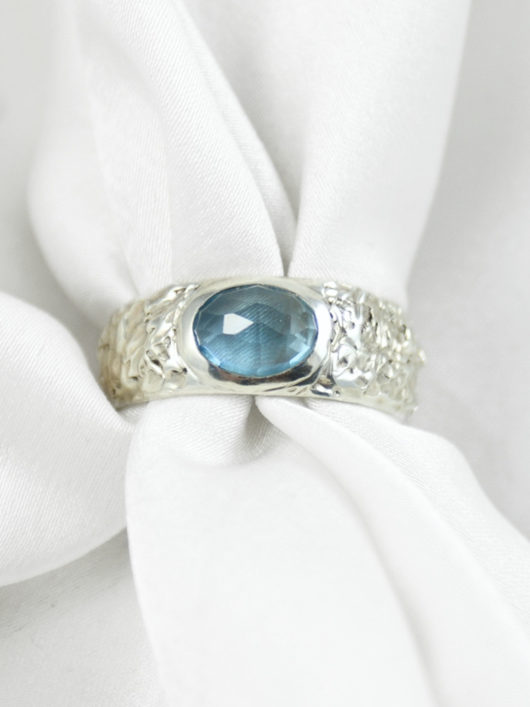 Owalny topaz Swiss Blue w srebrnym sygnecie z nieregularną fakturą ręcznie robionym HerRing.